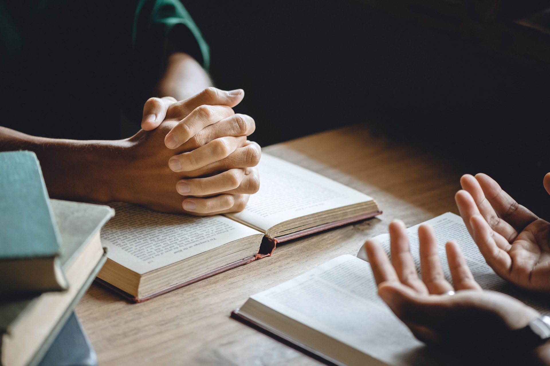 Groupe chrétien de personnes se tenant la main priant le culte pour croire et la Bible sur une table en bois pour le concept de réunion de dévotion ou de prière. n